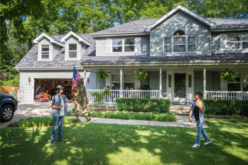 American family playing catch outside of house.