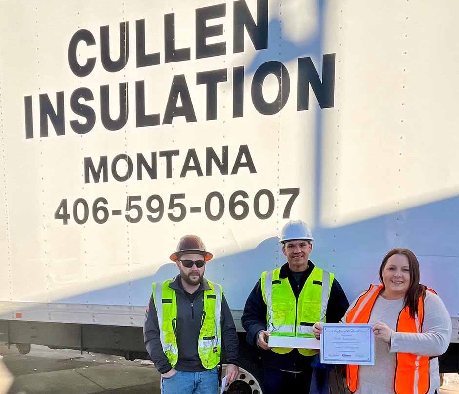 Three Cullen Insulation workers wearing safety vests standing in front of company trailer in Montana with certificate