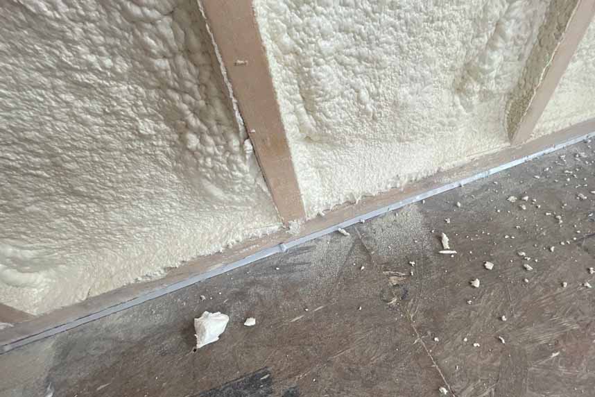 Detail of spray foam bridging between stud bottom plate and concrete slab, providing an effective air seal. Detail of spray foam bridging between stud bottom plate and concrete slab, providing an effective air seal.
