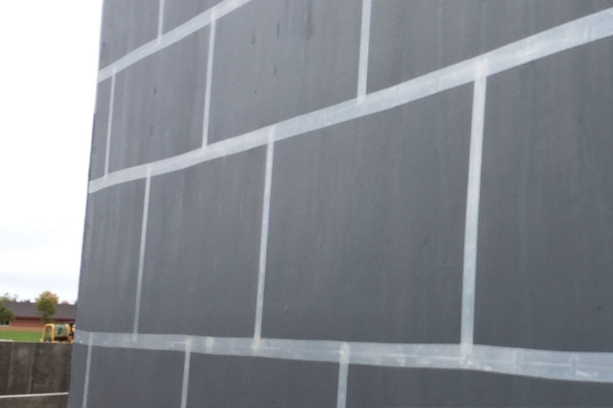 Close-up of a foundation wall with taped seams creating an air barrier over rigid sheathing during construction.